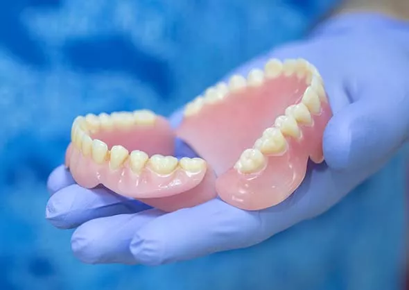 Partial dentures displayed on a hand.